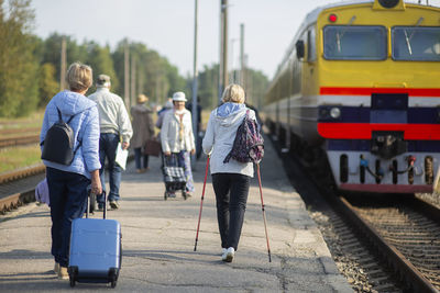 Rear view of people walking on railroad track