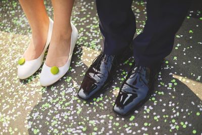 Low section of couple standing on street covered with confetti