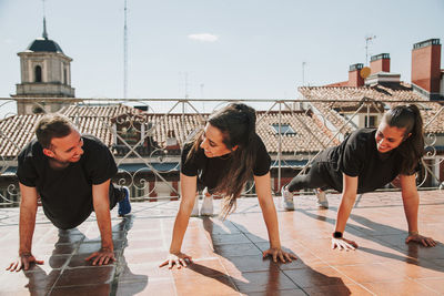 Three people doing push-ups on a rooftop