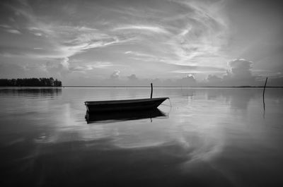 Boat moored in lake against sky