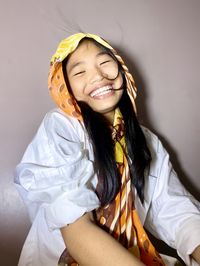 Portrait of young woman wearing hijab while standing against white background
