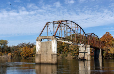 Broken bridge over river against sky