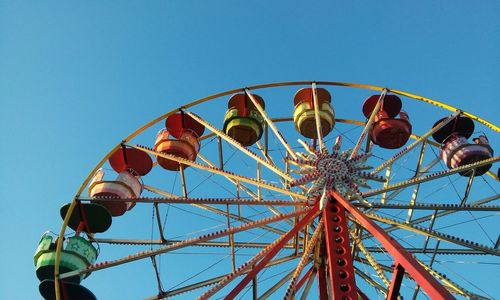 Low angle view of ferris wheel against clear blue sky