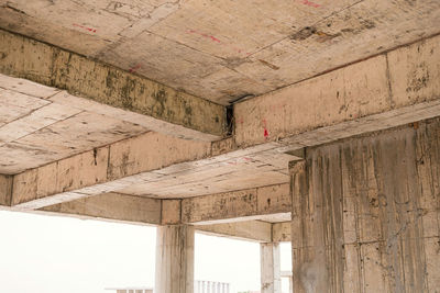 Looking up to see the size of concrete beams against old and dilapidated concrete floors. beams.