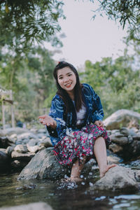 Portrait of smiling young woman sitting on rock