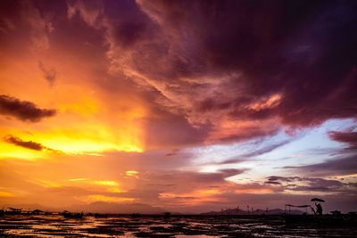 Scenic view of lake against cloudy sky during sunset