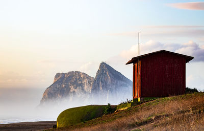 Shack structure by sea against sky during sunset