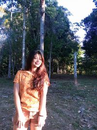 Portrait of smiling young woman standing against trees