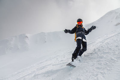 Young stylish girl or woman in motion snowboarding in the mountains