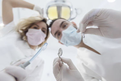 Low angle portrait of dentist with nurse holding medical equipment in hospital