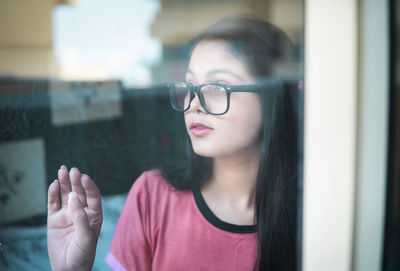 Young woman looking through window