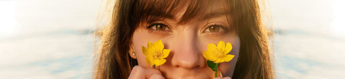 Close-up portrait of beautiful young woman against yellow sky