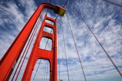 Low angle view of suspension bridge against cloudy sky