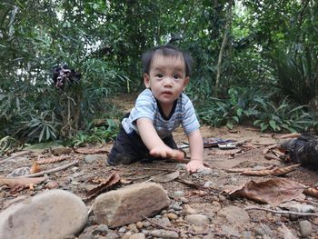 Portrait of cute boy crawling on field