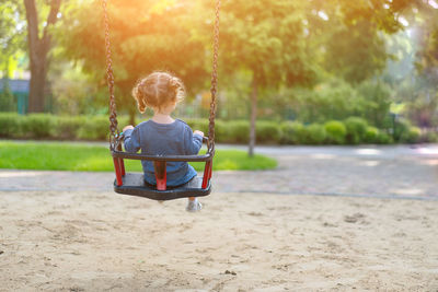 Rear view of girl on swing at park
