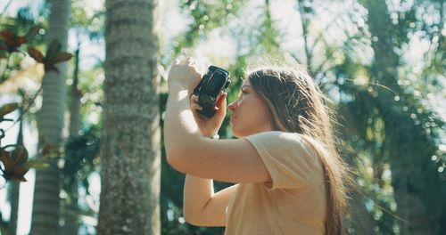 Woman photographing through smart phone outdoors