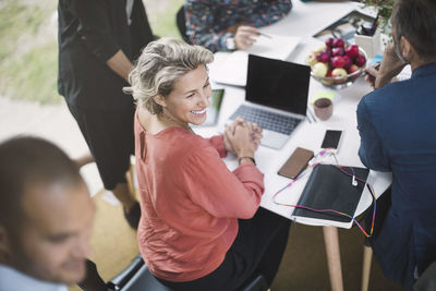 Happy businesswoman sitting at desk with colleagues in portable office truck