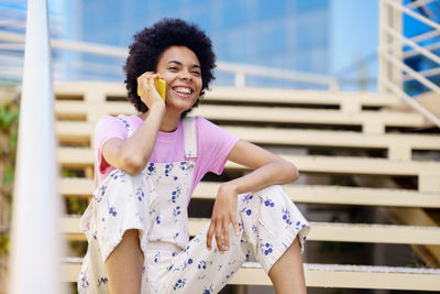 Smiling woman talking on phone sitting on steps