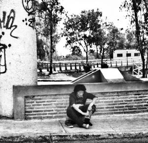 Boy sitting on tree in city