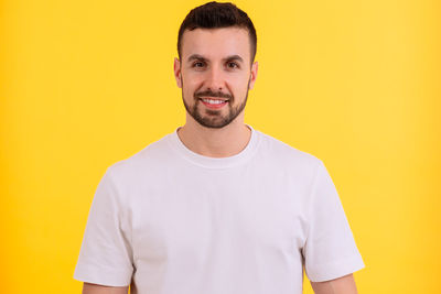 Young man standing against yellow background