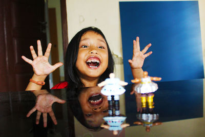 Cute girl laughing while sitting by table at home