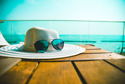 Close-up of hat on table by swimming pool against sea