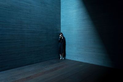 Woman photographing with camera while standing against wall