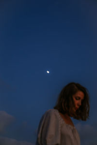 Rear view of woman standing against blue sky