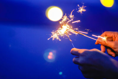 Woman hands holding illuminated sparklers at night