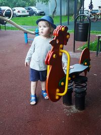 Full length of boy standing by spring ride at playground