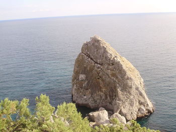 Rock formation by sea against sky