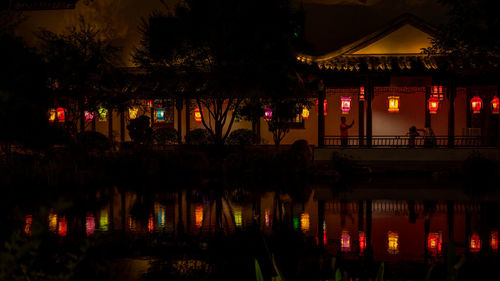 Silhouette trees by illuminated building at night