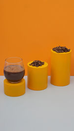 Still life photography of coffe bean and a cup coffee drink on orange background