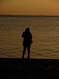 Silhouette people standing on beach during sunset