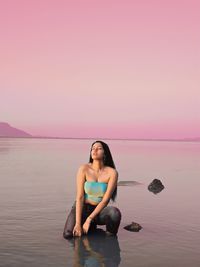 Full length of woman relaxing on beach against sky during sunset