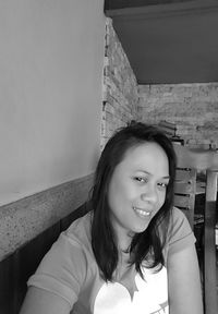 Portrait of smiling young woman against wall at home