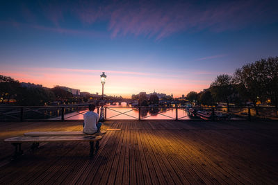 Silhouette bridge over river against sky at sunset
