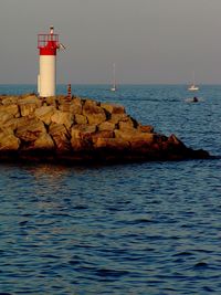 Lighthouse by sea against sky