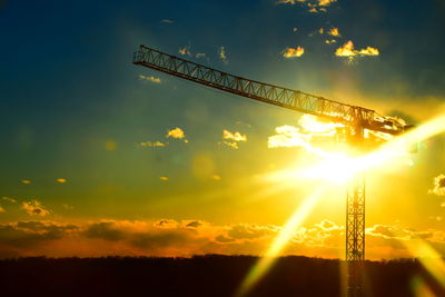 Low angle view of silhouette cranes against sky during sunset