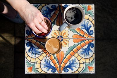 Cropped hand having coffee on stool