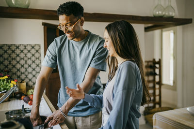 Happy young man and woman washing dishes together in kitchen sink at home