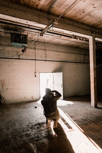 Young man with backpack crouching in abandoned room