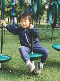 Portrait of boy sitting on play equipment at playground