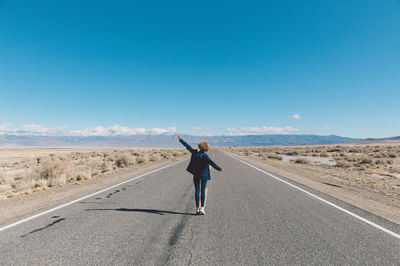 Woman standing on road against clear sky