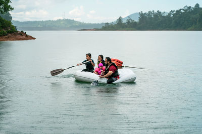 Family wearing life jackets paddling on an inflatable boat in kenyir lake, malaysia.