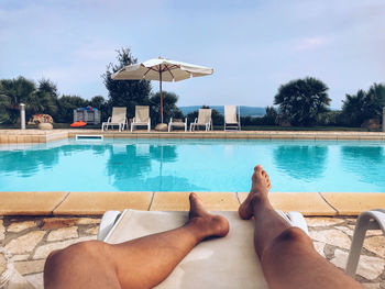 Low section of man relaxing in swimming pool