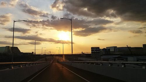 Road in city against sky during sunset