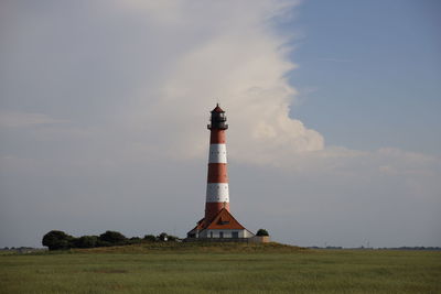 Lighthouse on field against sky