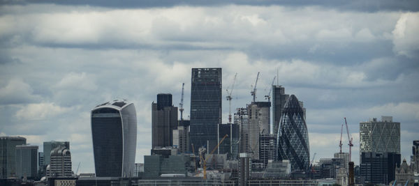 Skyscrapers in city against cloudy sky