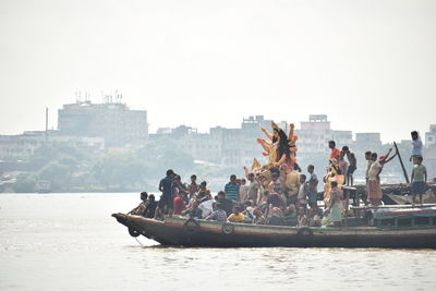 People on boat in river against clear sky